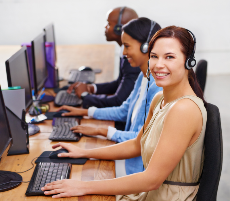 Customer service staff wearing headsets at a row of computers