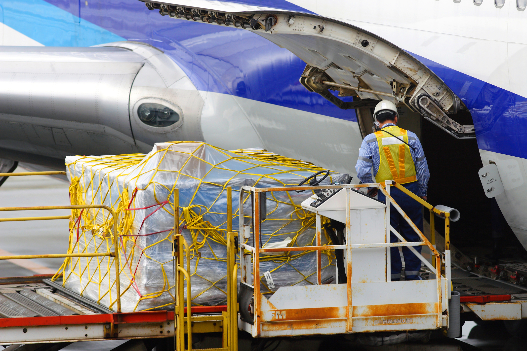 Wrapped cargo on a loader beside an aircraft's open cargo door
