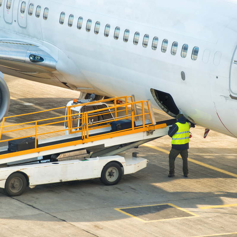 A ground crew worker loading cargo into the hold of a passenger aircraft