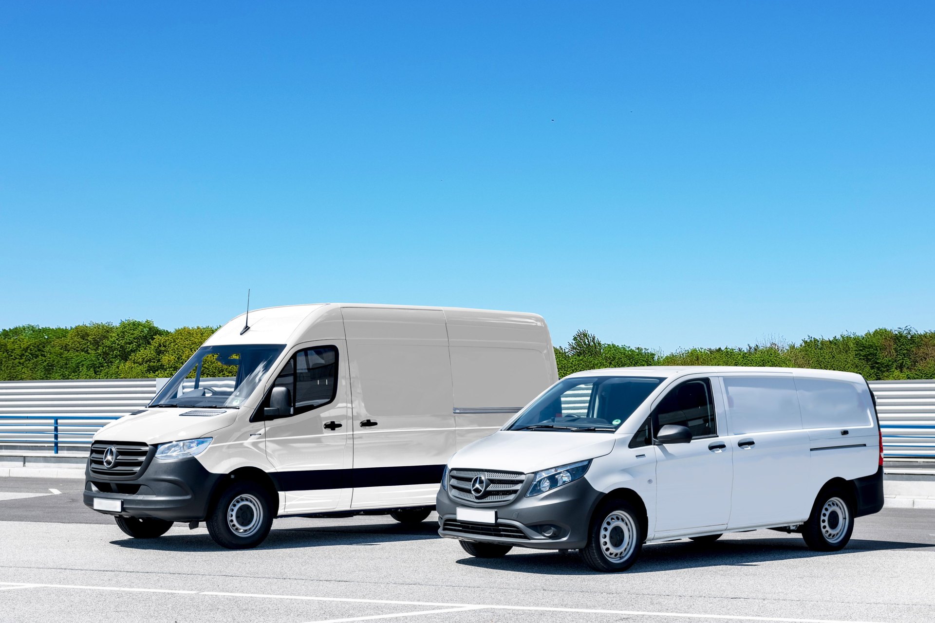 Two white delivery vans parked under a clear sky