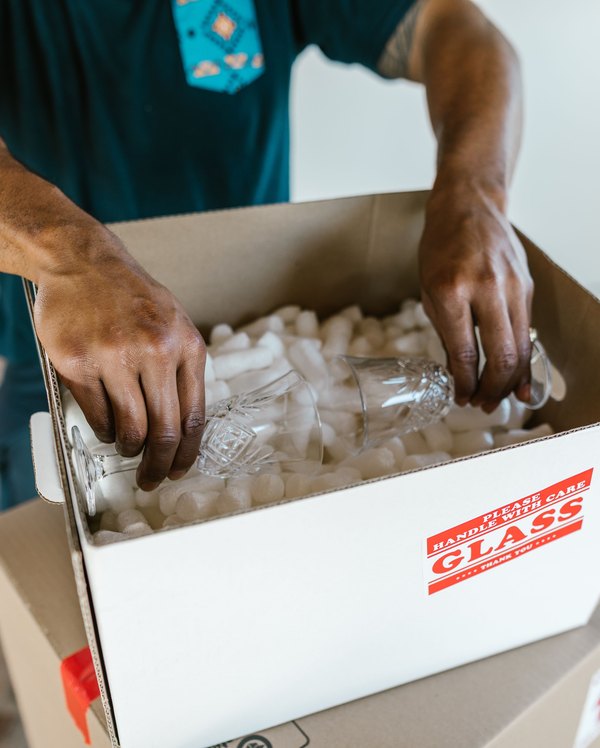 Hands carefully packing glassware into a box