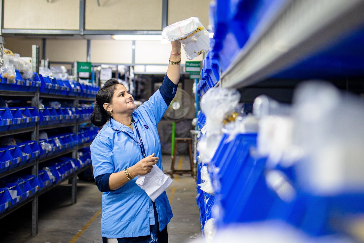 A warehouse worker organising parts in blue bins