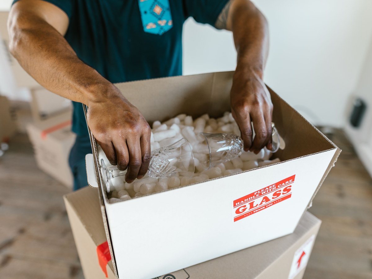 Hands carefully packing glassware into a box